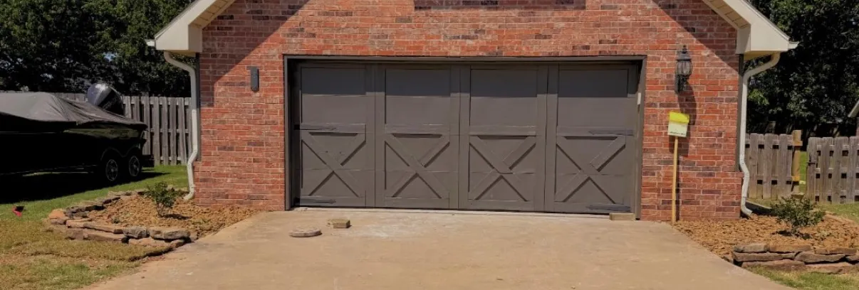 Brick garage front with a clean concrete driveway and a stone edged bed running along the side