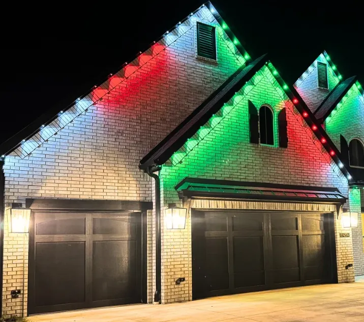 Three car garage on a white brick home lit in red and green at night