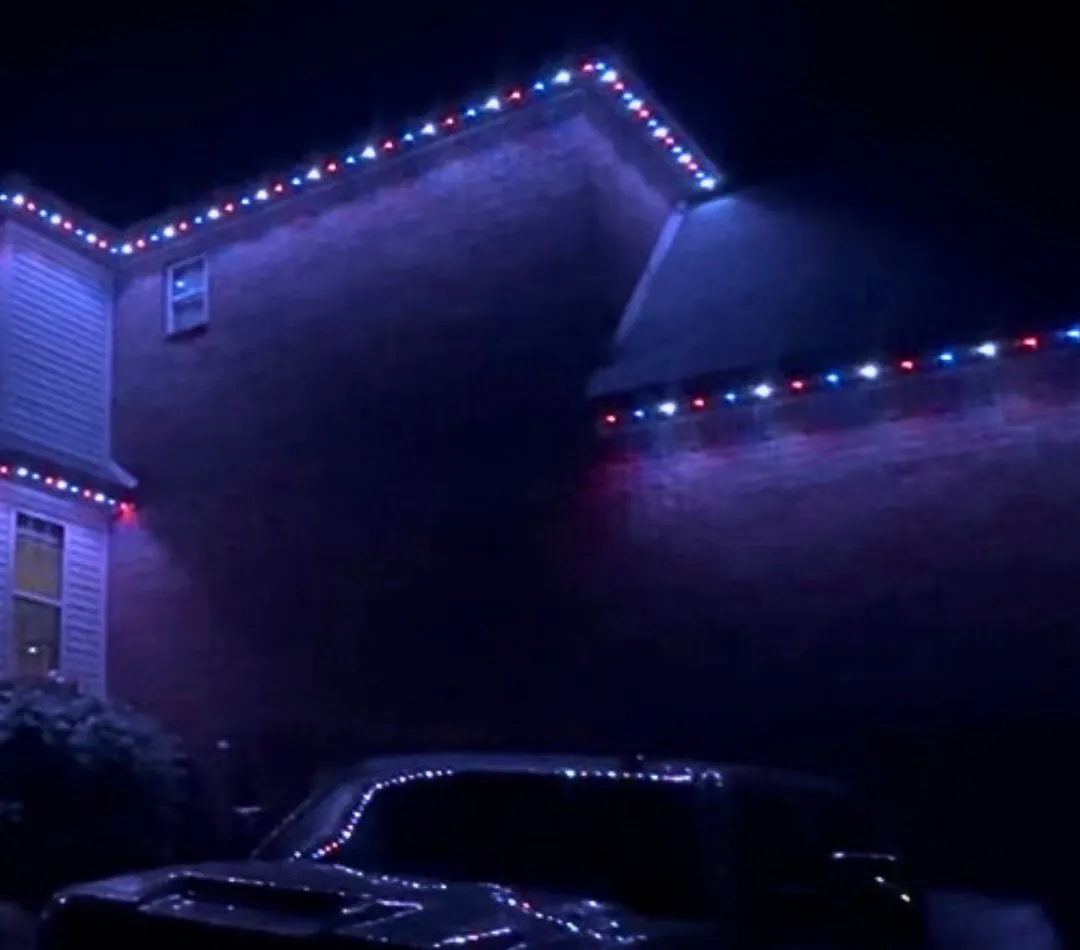 Brick two story with red, white and blue lighting along the rooflines and a truck outlined in the same colors