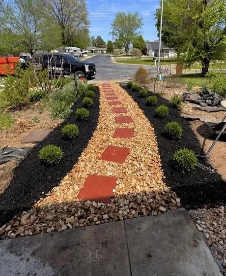 Stepping stone path set in river rock between two planted mulch beds running out to the street