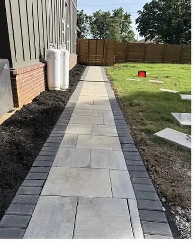 New paver walkway with a charcoal border running down the side of a house past a fresh mulch bed