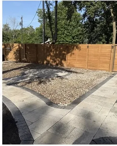 Paver patio and pea gravel running up to a wood privacy fence