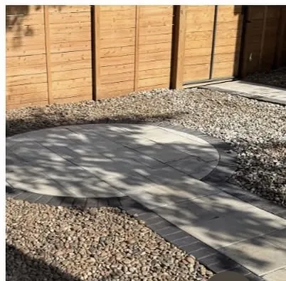 Finished circular paver patio surrounded by river rock in dappled shade