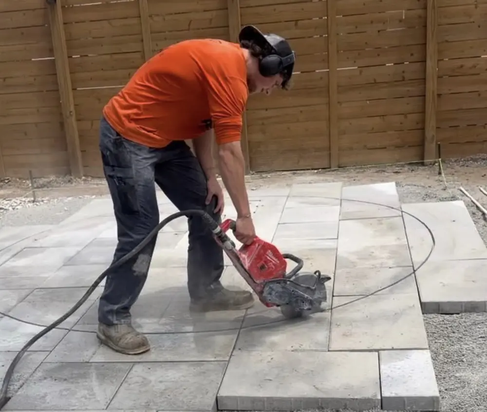 Peak installer cutting a paver with a cut off saw on a new patio