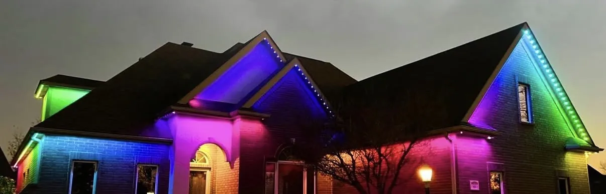Brick ranch at night with each gable washed in a different color, green, blue, purple and red